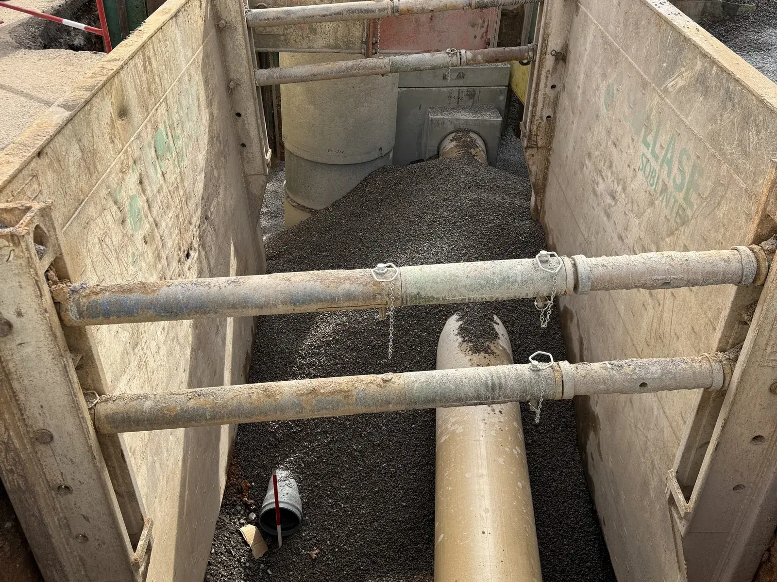 Canalisation posée au fond d’une tranchée blindée en centre-ville, avec un regard en arrière-plan