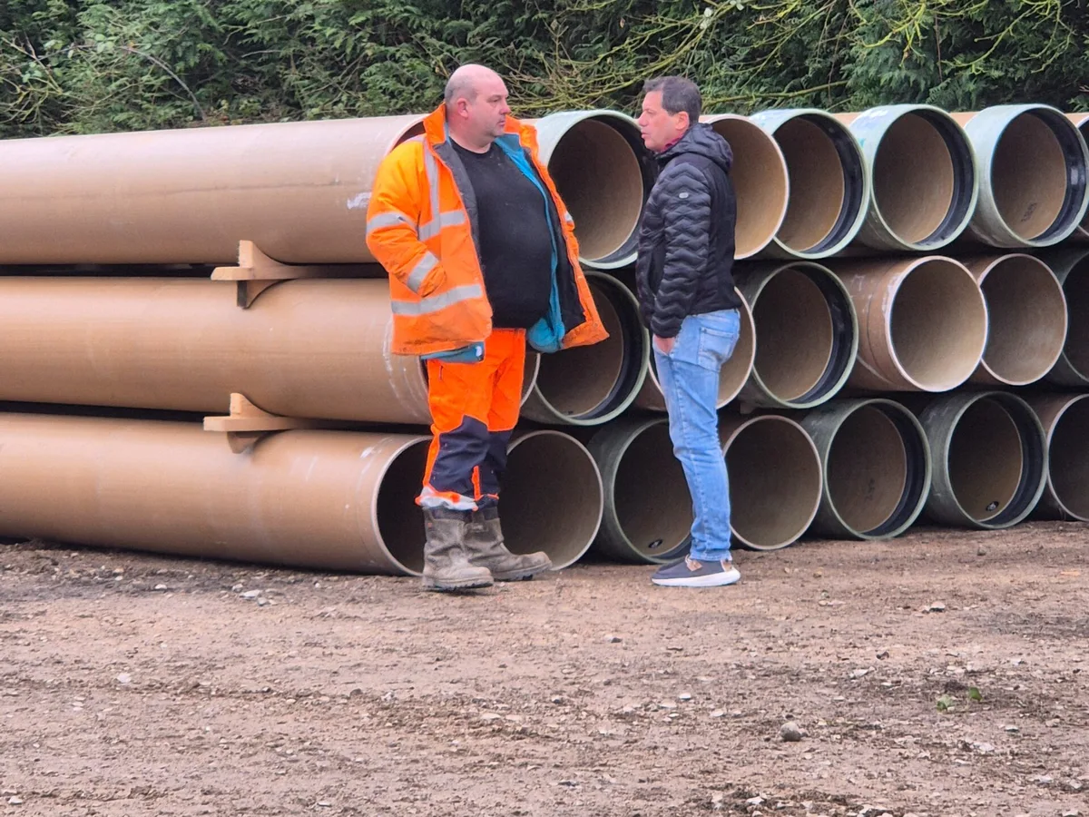 Conversación en obra frente a tuberías de PRFV apiladas en la obra de Domart