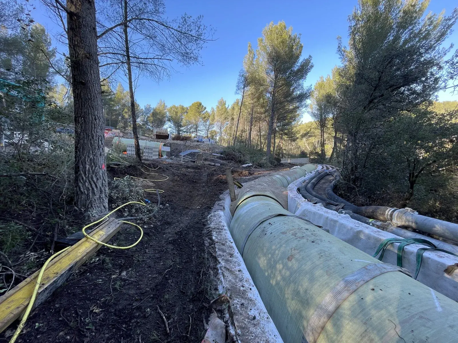 Tubería instalada en una zanja en medio de un pinar, en una obra de rehabilitación de un canal